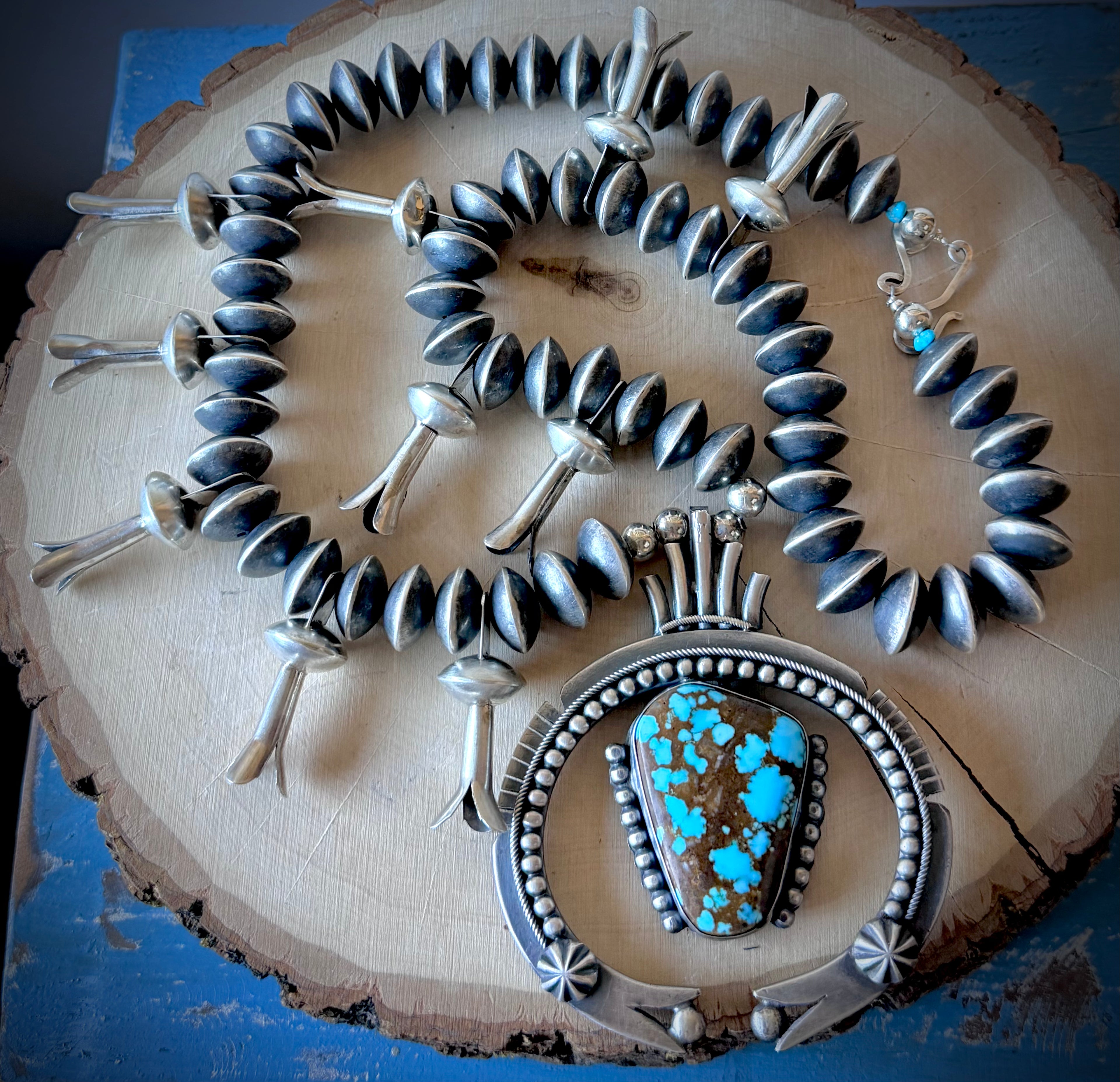 ColoradoJo Andy Marion Pilot Mountain Turquoise & Sterling Squash Blossom Necklace on wood slab view